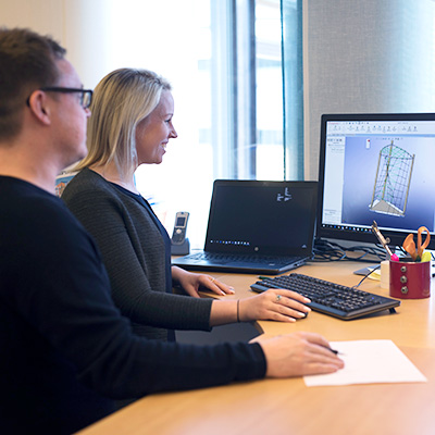 Image of office workers, they are designers at HAGS, looking at a screen and smiling.